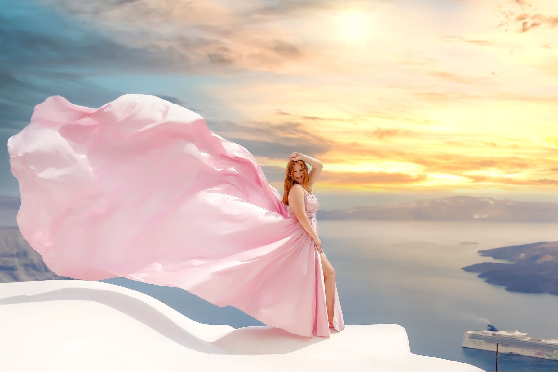 A woman in a flowing Santorini flying dress poses against the stunning backdrop of the caldera.