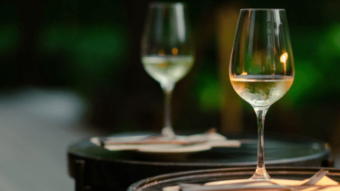 Glass of Assyrtiko white wine served outdoors in Santorini, reflecting the island’s historic wine culture and relaxed tasting experience
